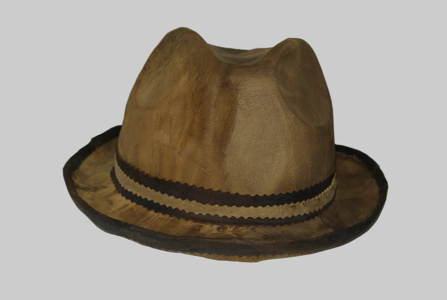 Brown amadou fedora hat with a black band on a white surface
