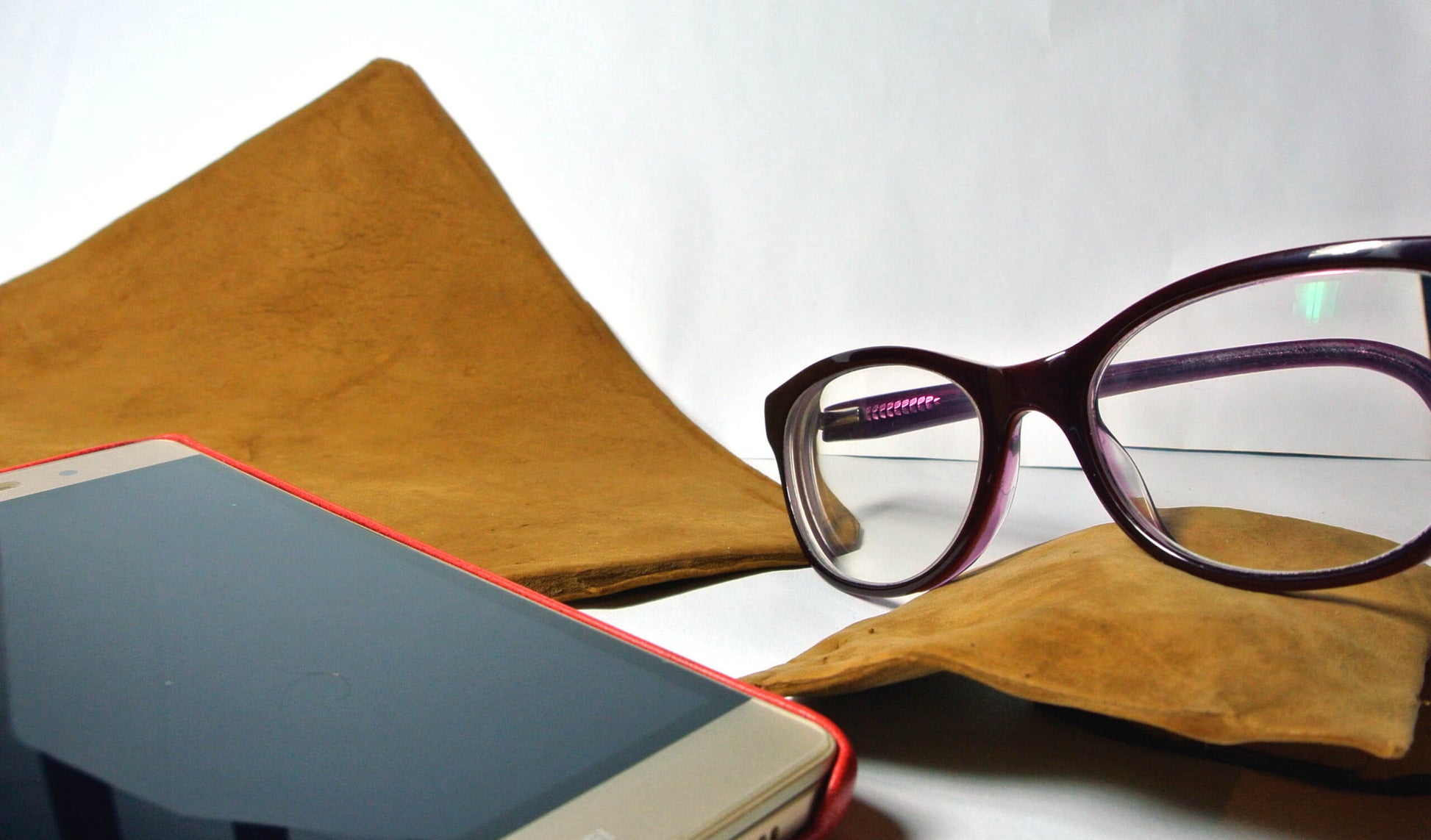 Smartphone, glasses, and the amadou lens and camera clener  on a white surface