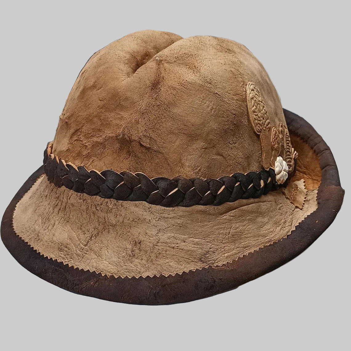 Brown amadou hat with braided band on a white surface